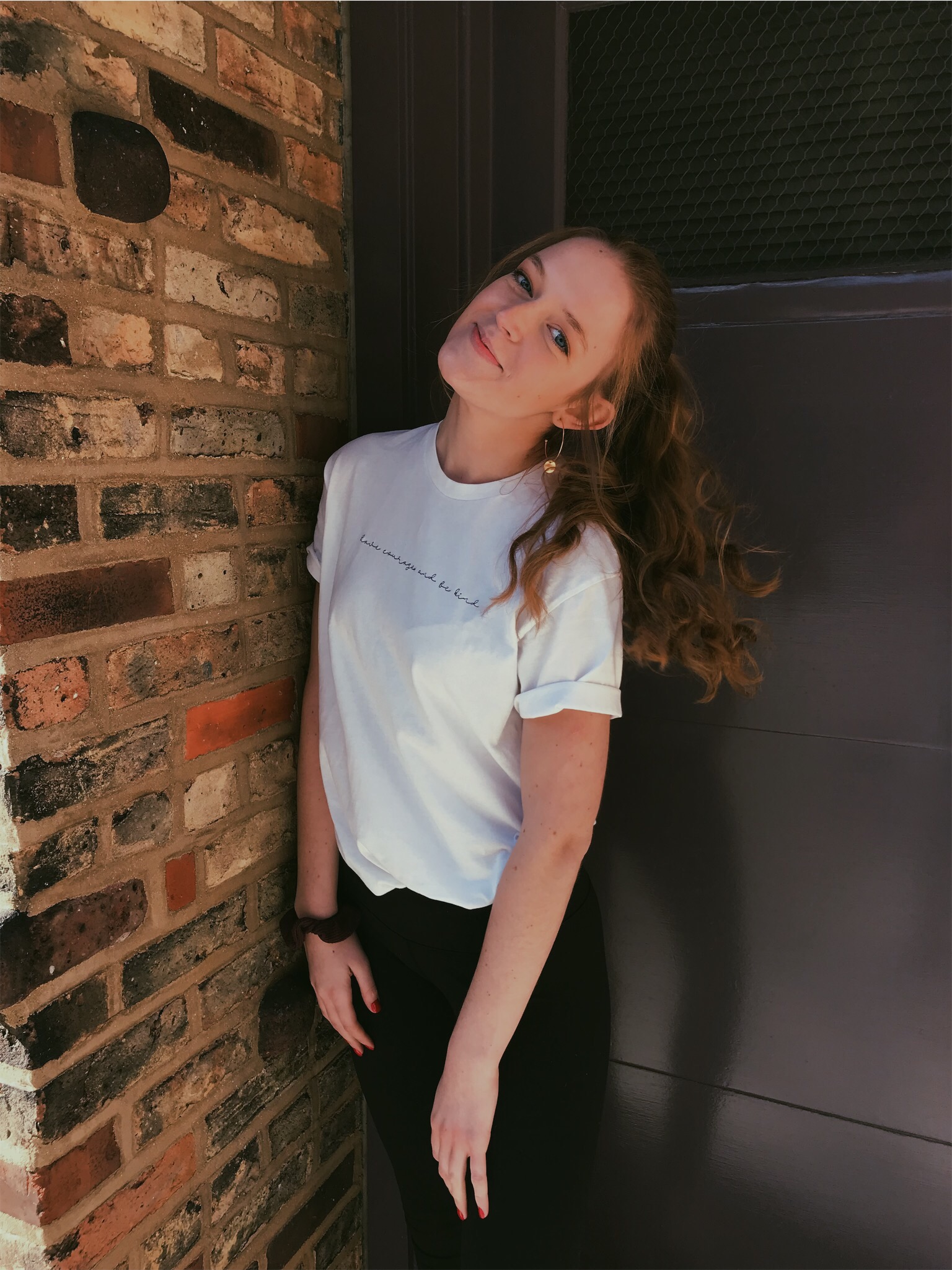 Image of Casey Kazich smiling, standing next to a brick wall